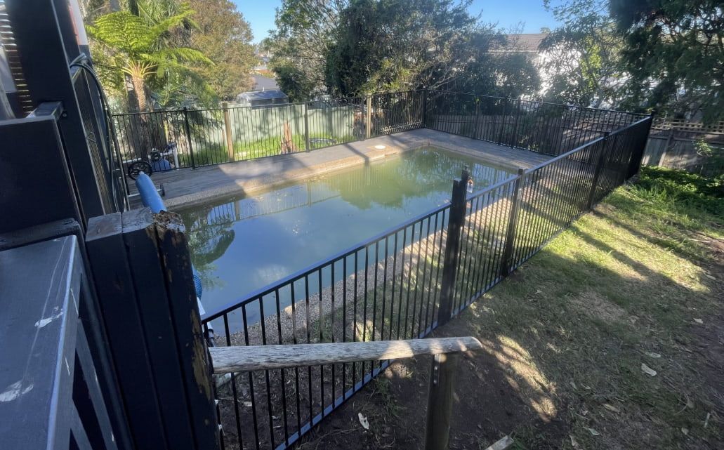 A Pool Surrounded by a Fence — Pride Carpentry & Maintenance In Berkeley Vale, NSW