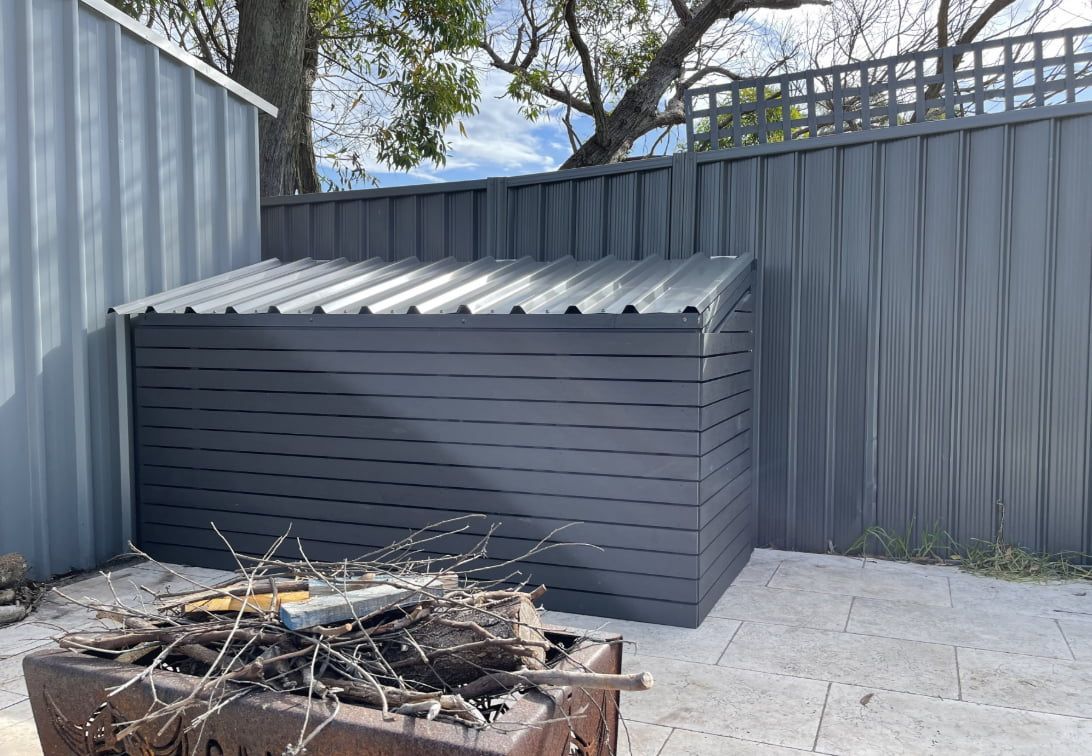 A Grey Storage Box Next to a Fire Pit — Pride Carpentry & Maintenance In Berkeley Vale, NSW