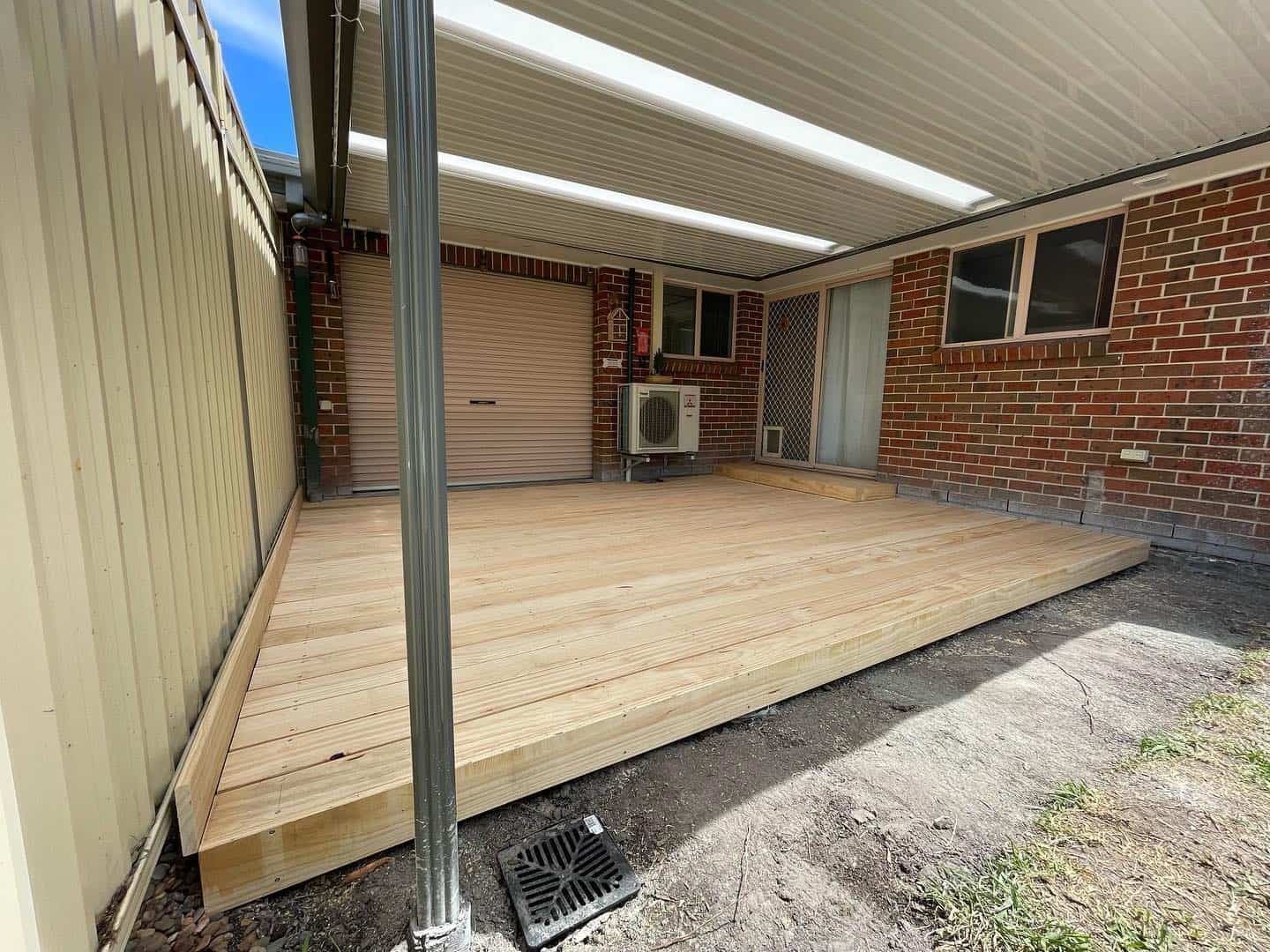 A Wooden Deck Alongside a Door and a Brick Wall — Pride Carpentry & Maintenance In Berkeley Vale, NSW