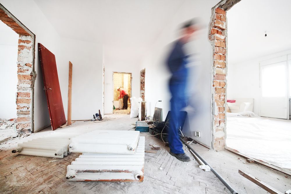 Construction workers renovating the interior of a house with exposed brick walls, scattered material