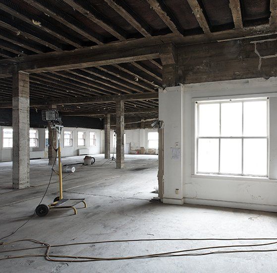 Interior Of A Large, Empty Building Under Renovation With Concrete Floors And Exposed Beams
