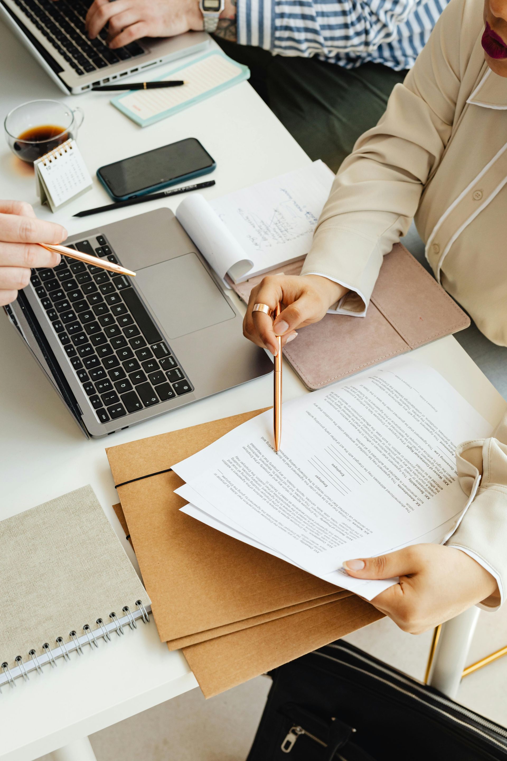 A calculator , a notebook , and a pen are on a table.