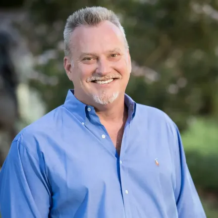 A man in a blue shirt is smiling for the camera