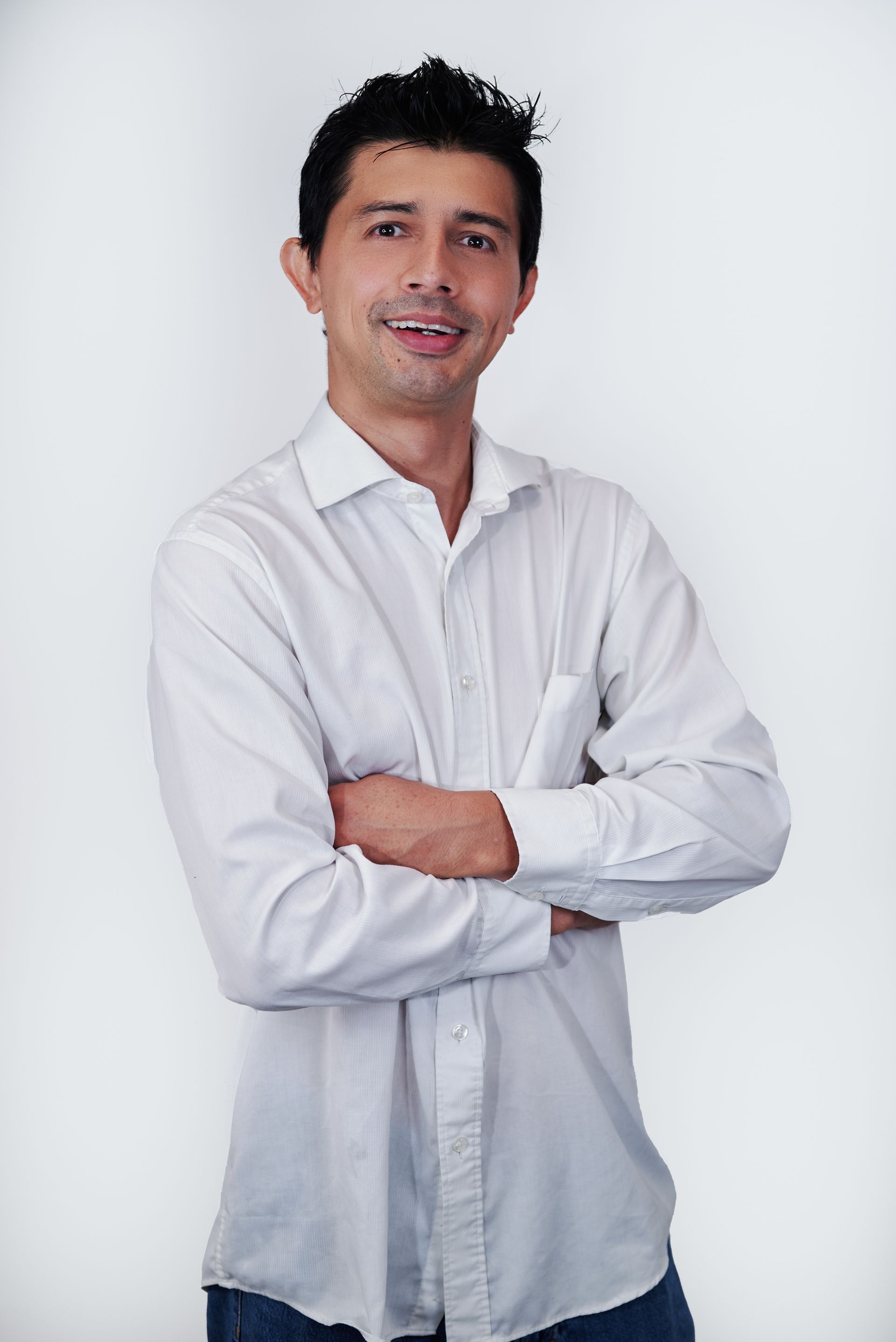 A man in a white shirt is standing with his arms crossed.