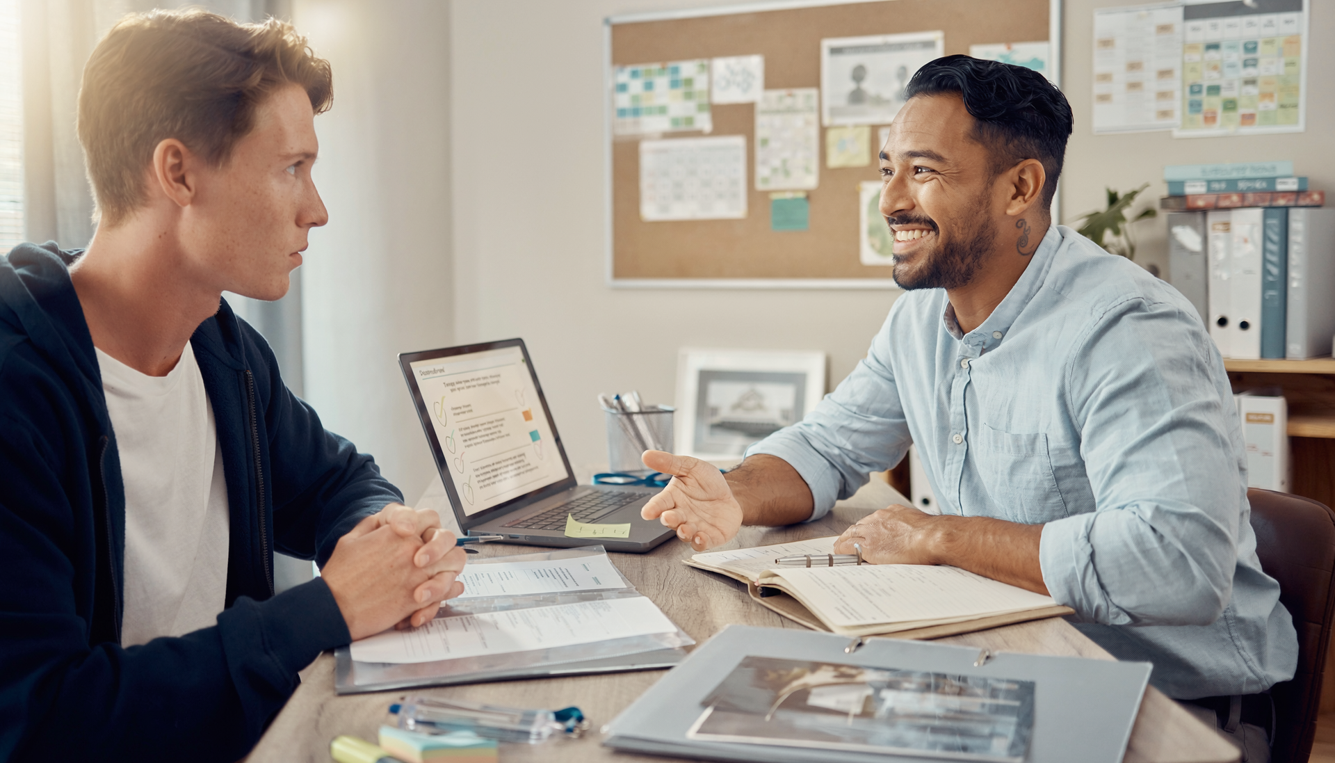 A group of five friends walks together outdoors on a sunny, palm-lined path, laughing and talking in casual clothing.