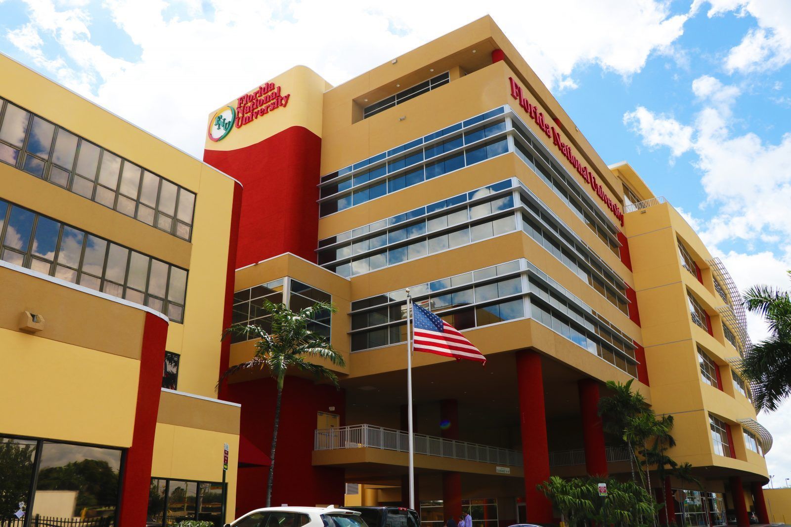 Modern multi-story hospital building with red and yellow accents and an American flag out front
