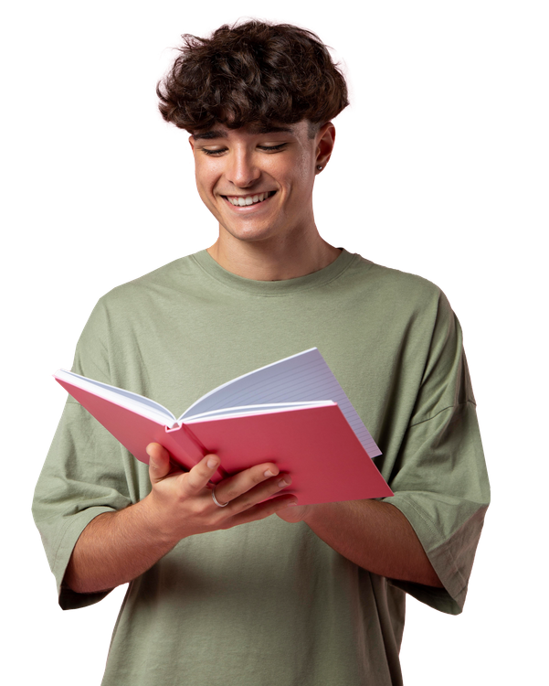 A young man is reading a pink book and smiling.