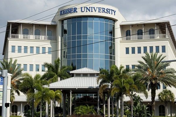 Keiser University building with glass facade and palm trees at the entrance