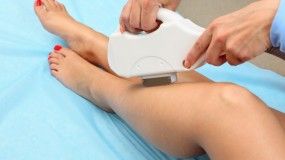 A woman is getting a laser hair removal treatment on her legs.