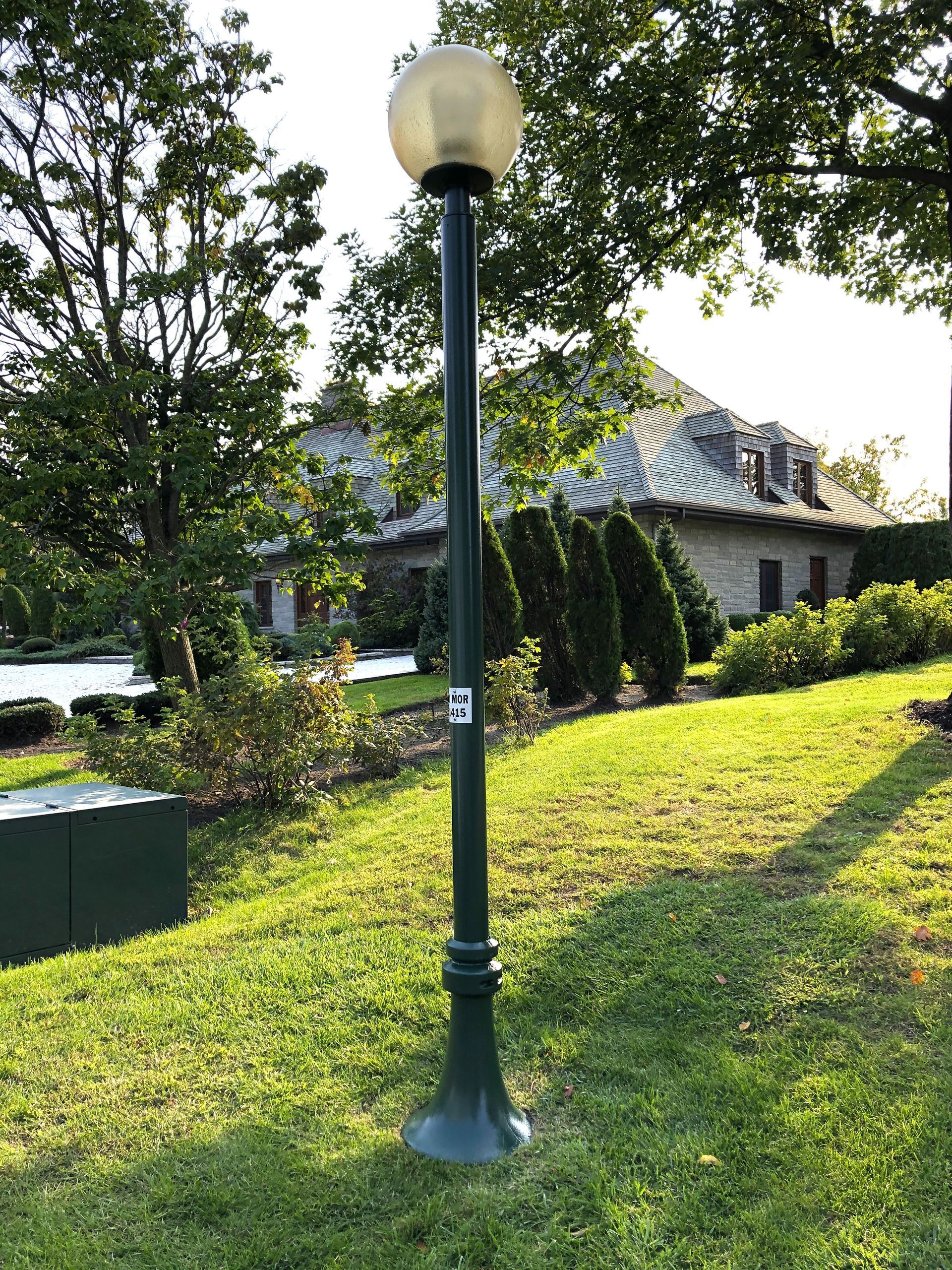 Un lampadaire est posé dans l'herbe devant une maison.