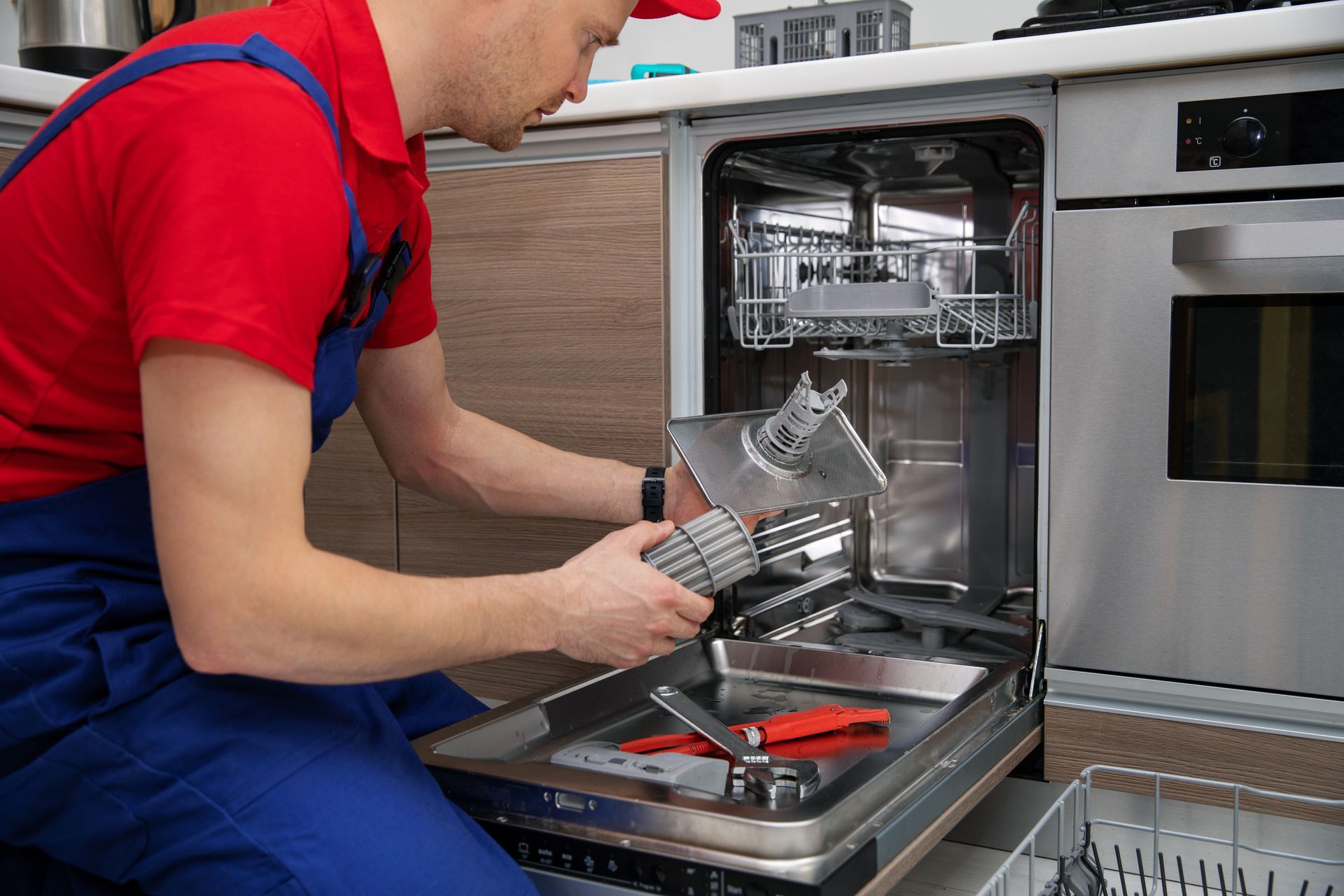 A man is fixing a dishwasher in a kitchen.