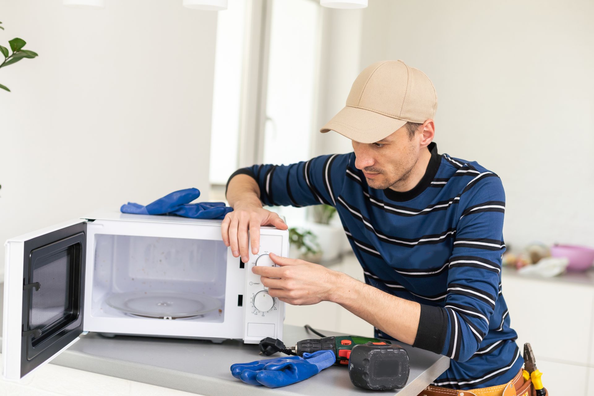 A man is fixing a microwave oven in a kitchen.