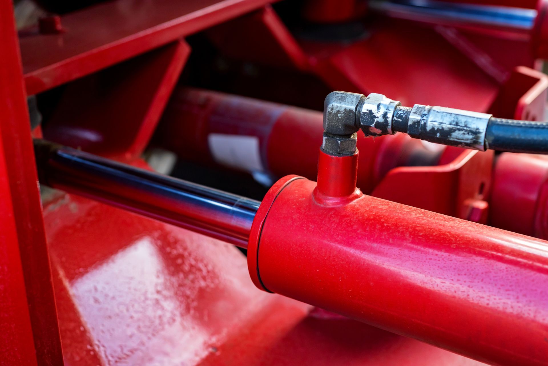 Un gros plan d'un cylindre hydraulique rouge sur une machine.