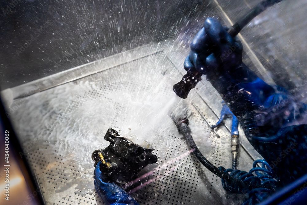 Une personne nettoie une machine avec un tuyau et de l'eau.