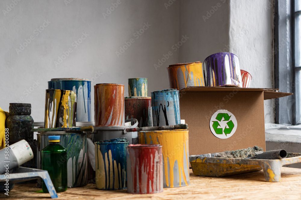 Un tas de pots de peinture sont empilés les uns sur les autres sur une table en bois.