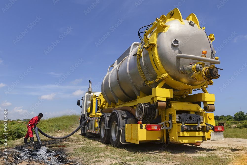 Un homme se tient à côté d'un camion aspirateur jaune.