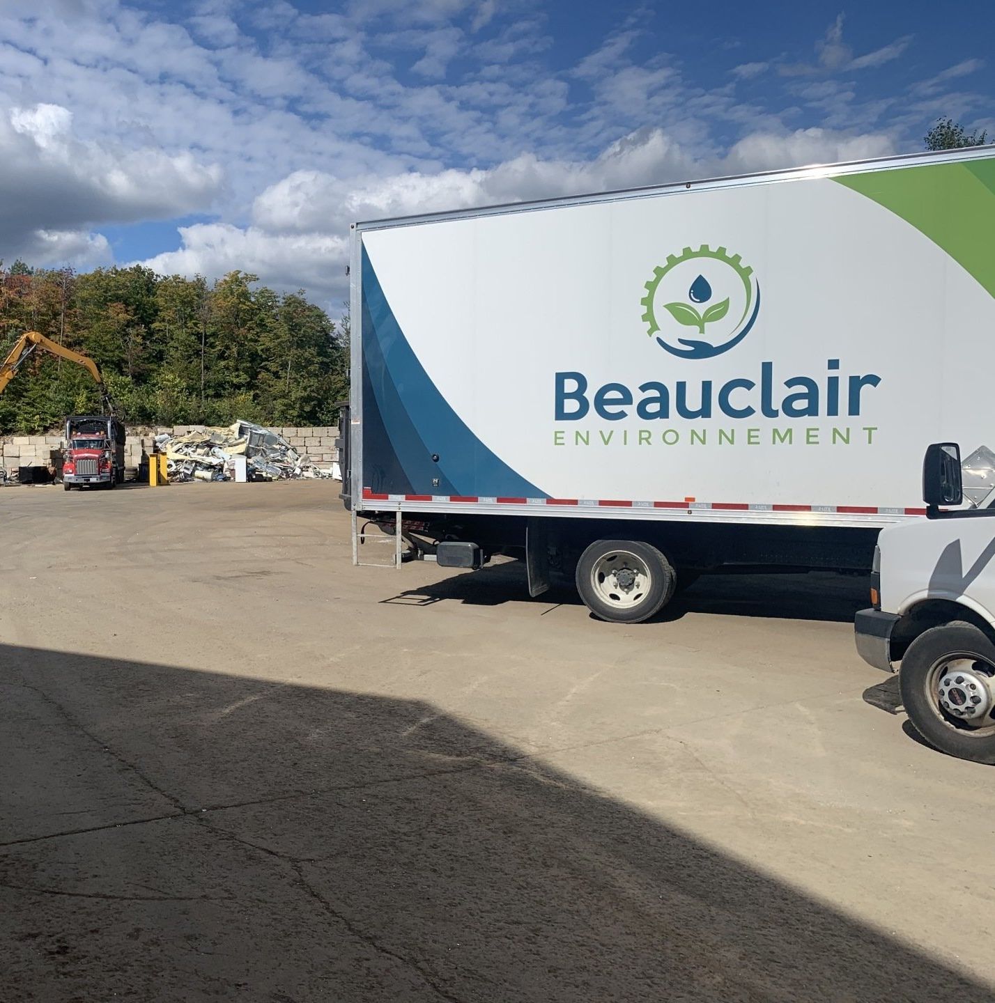 Un semi-camion avec le logo « Beauclair Environnement » stationné dans une installation de recyclage par une journée ensoleillée.
