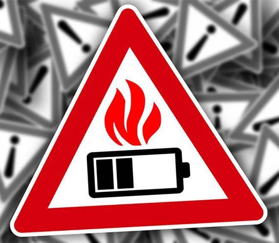 Un triangle rouge et blanc avec une batterie et des flammes dessus