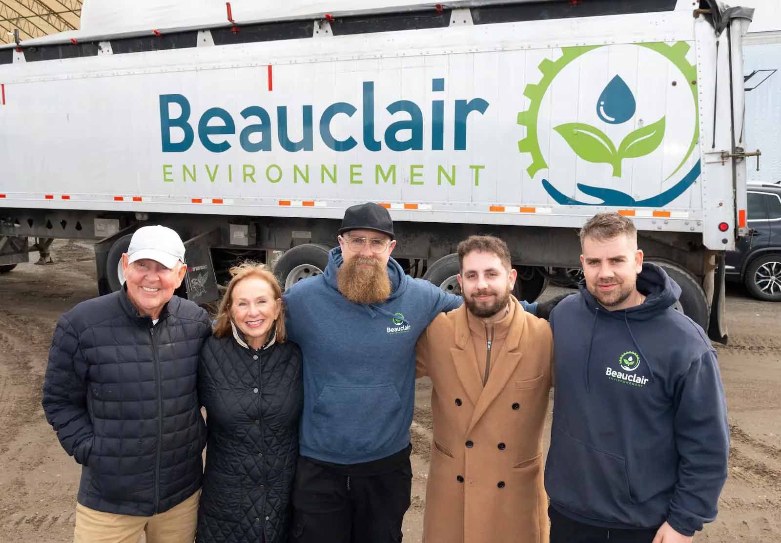 Un homme portant un casque écrit sur un presse-papiers devant une pile de barils