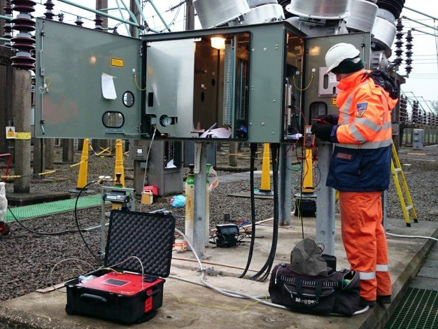 Un homme travaille sur un boîtier électrique avec la porte ouverte