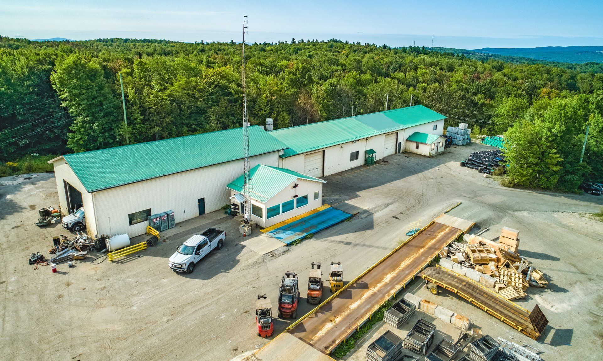 Installation industrielle avec toit végétalisé et forêt environnante, avec camions et engins lourds.