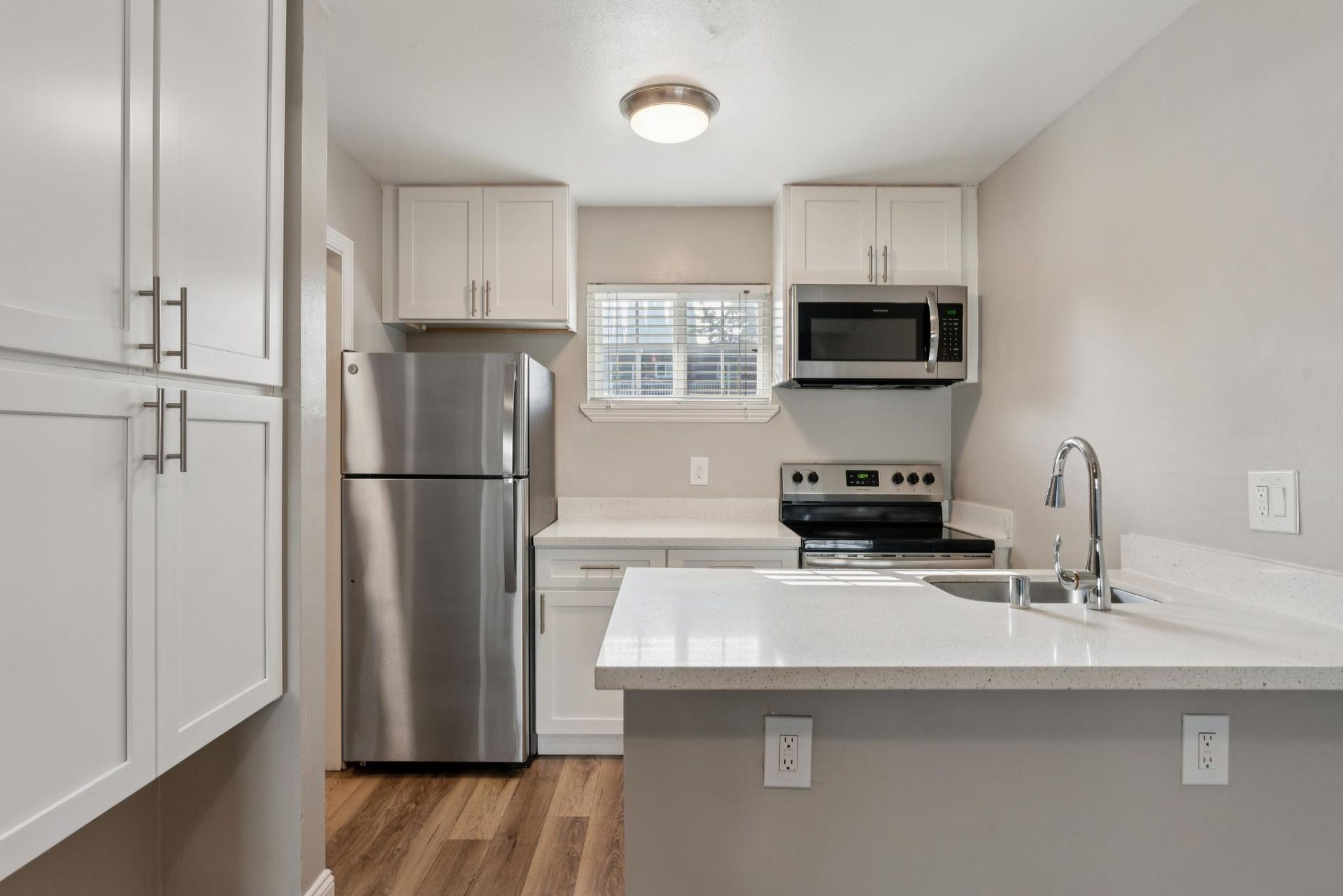 Bright, modern kitchen with white cabinets, stainless steel appliances, and a countertop island.