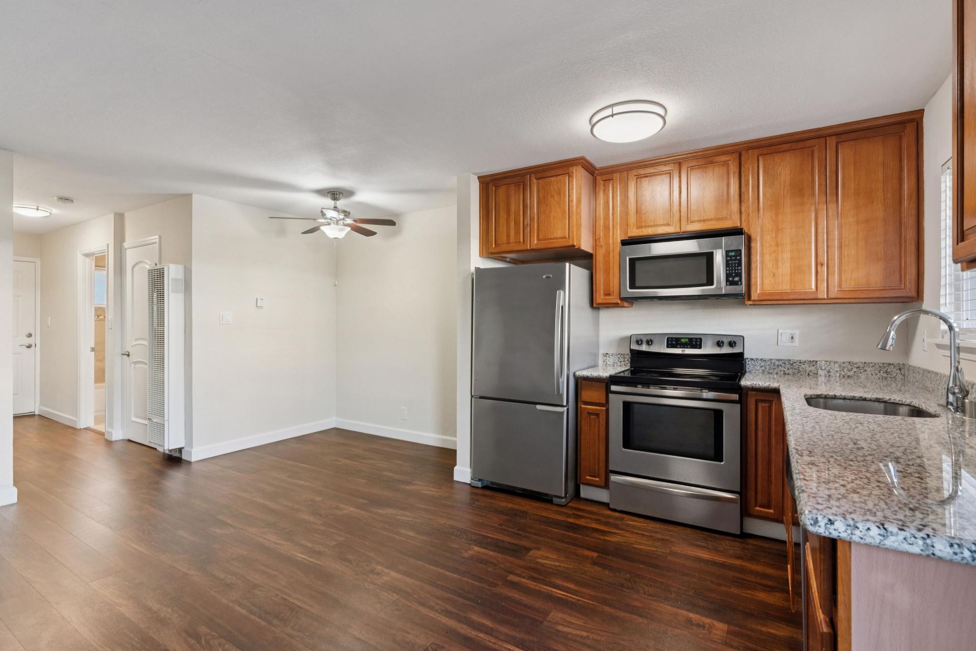 Kitchen with wood cabinets, stainless steel appliances, and dark wood floors.