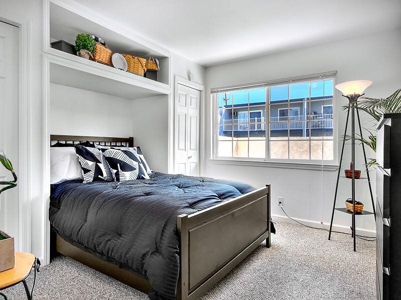 Cozy bedroom with a dark wood bed, built-in shelving, and a large window.