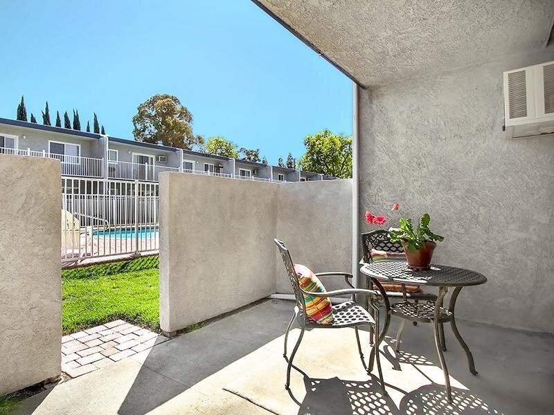 Balcony with round table and chairs, overlooking a pool area