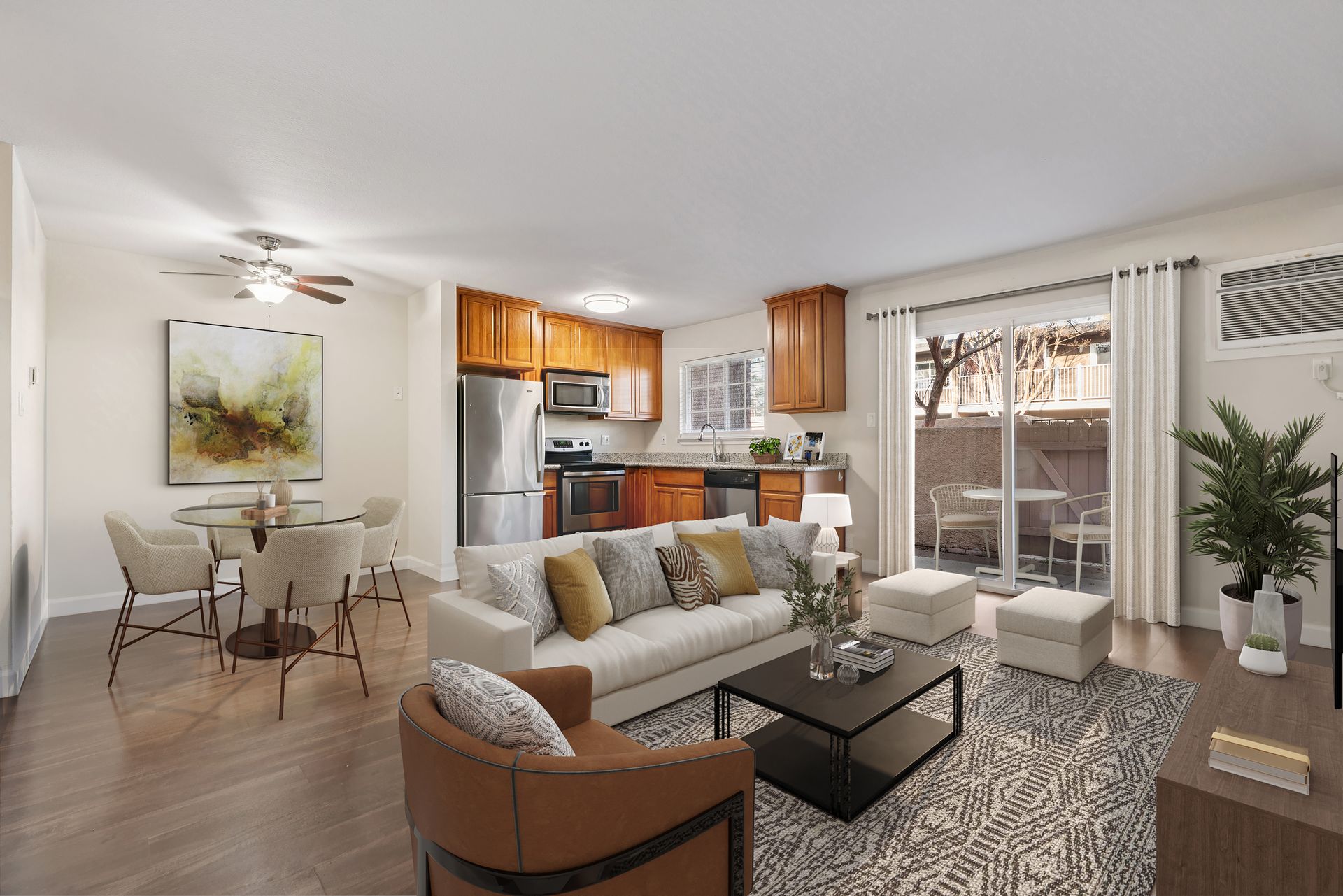 Open-concept living space with a kitchen, dining area, and living room. Neutral colors, wooden floors, and patio access.