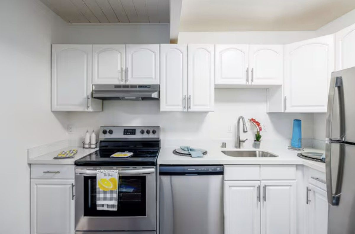 White kitchen with stainless steel appliances and cabinets.