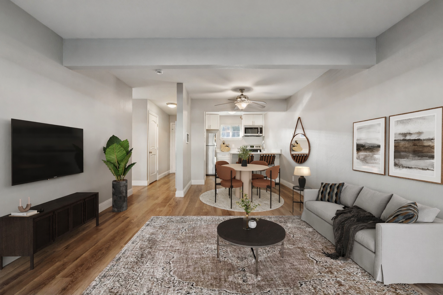Cozy living space with hardwood floors, dark TV console, round dining table, and modern furniture.