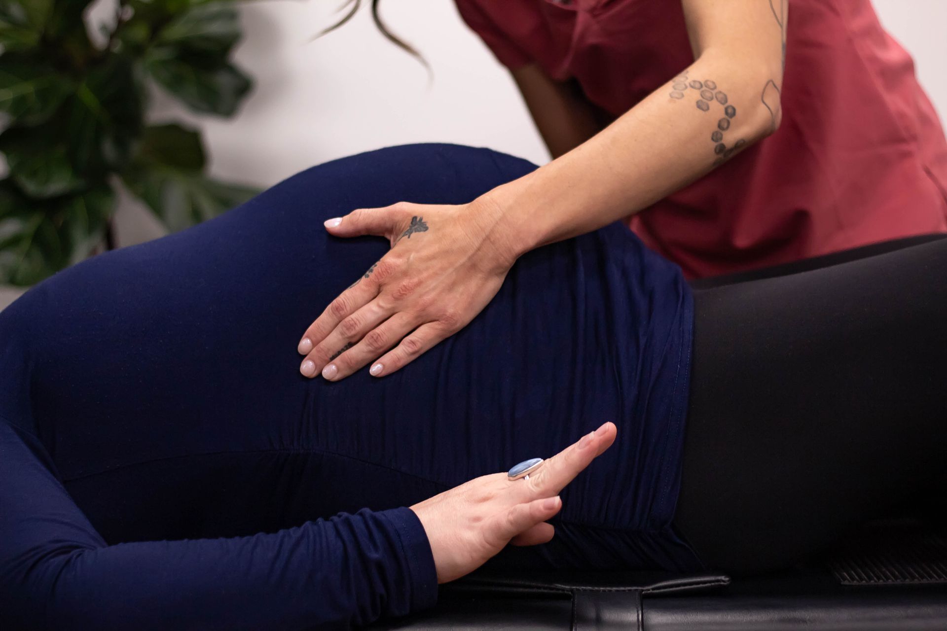 A pregnant woman is kneeling on the floor with an exercise ball.