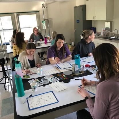 A group of women are sitting at tables in a classroom.