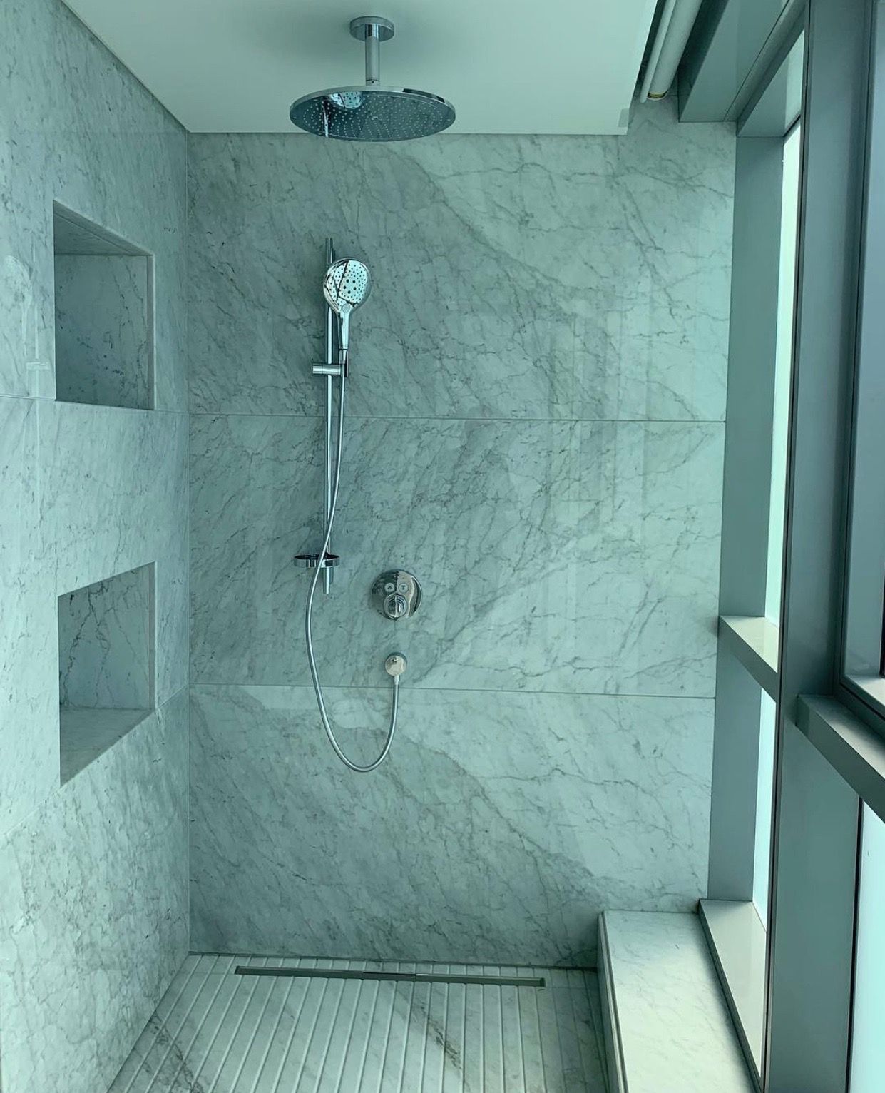 Patio with white furniture, manicured lawn, and a round marble table in a garden setting.