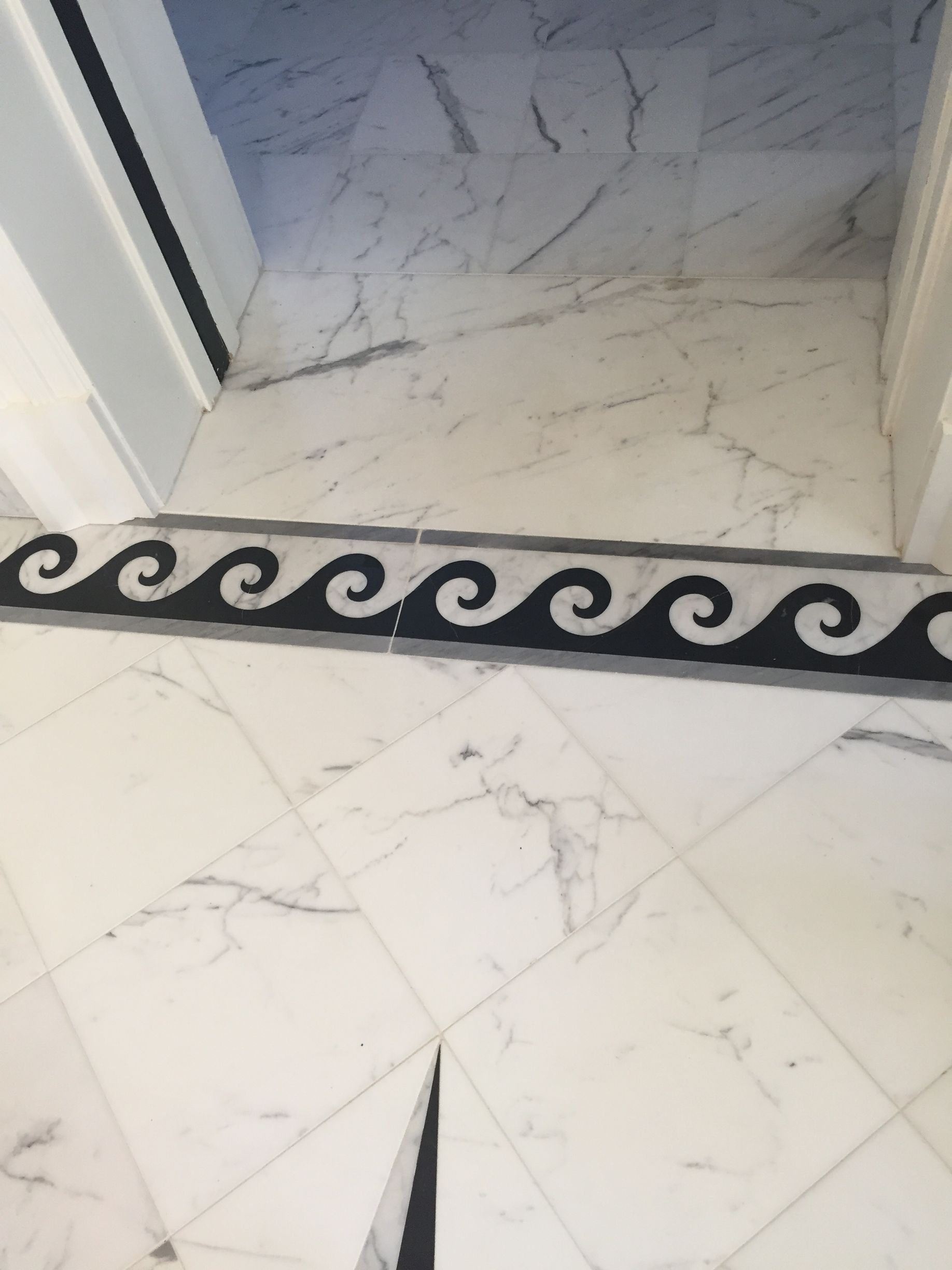 White marble floor with black wave-patterned border.
