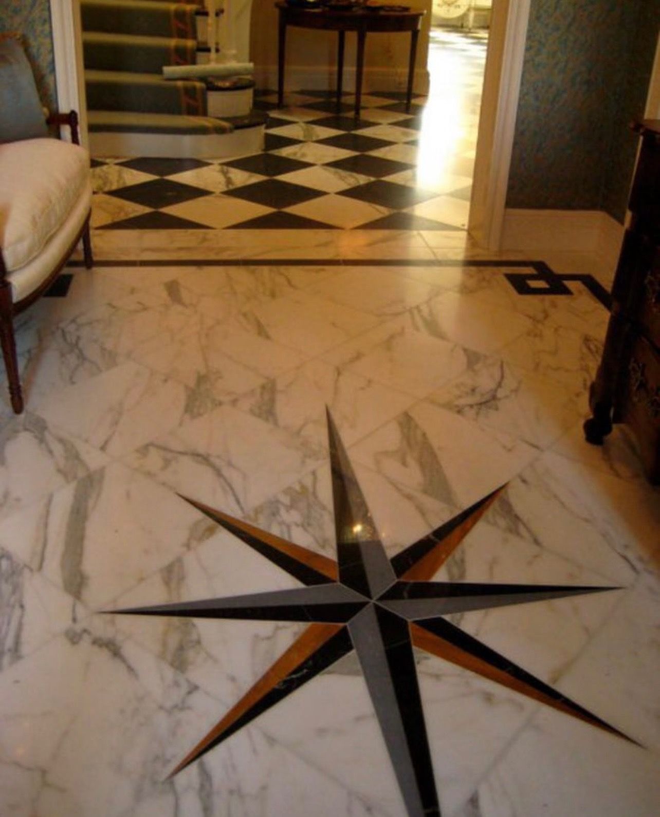 Marble floor with a compass rose design, leading to a checkered floor and staircase.