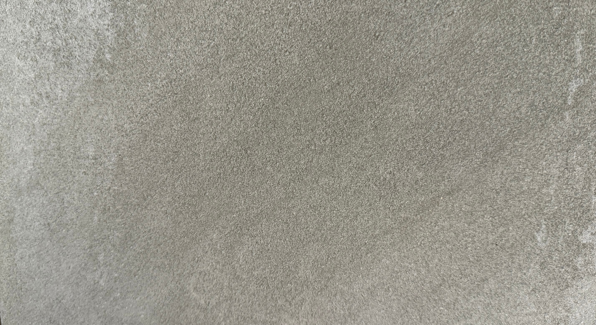 Gray, textured surface with curved, lighter-toned striations, resembling a sandy or stone-like texture.