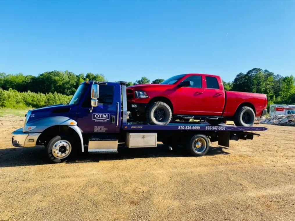 A red truck is being towed by a tow truck.