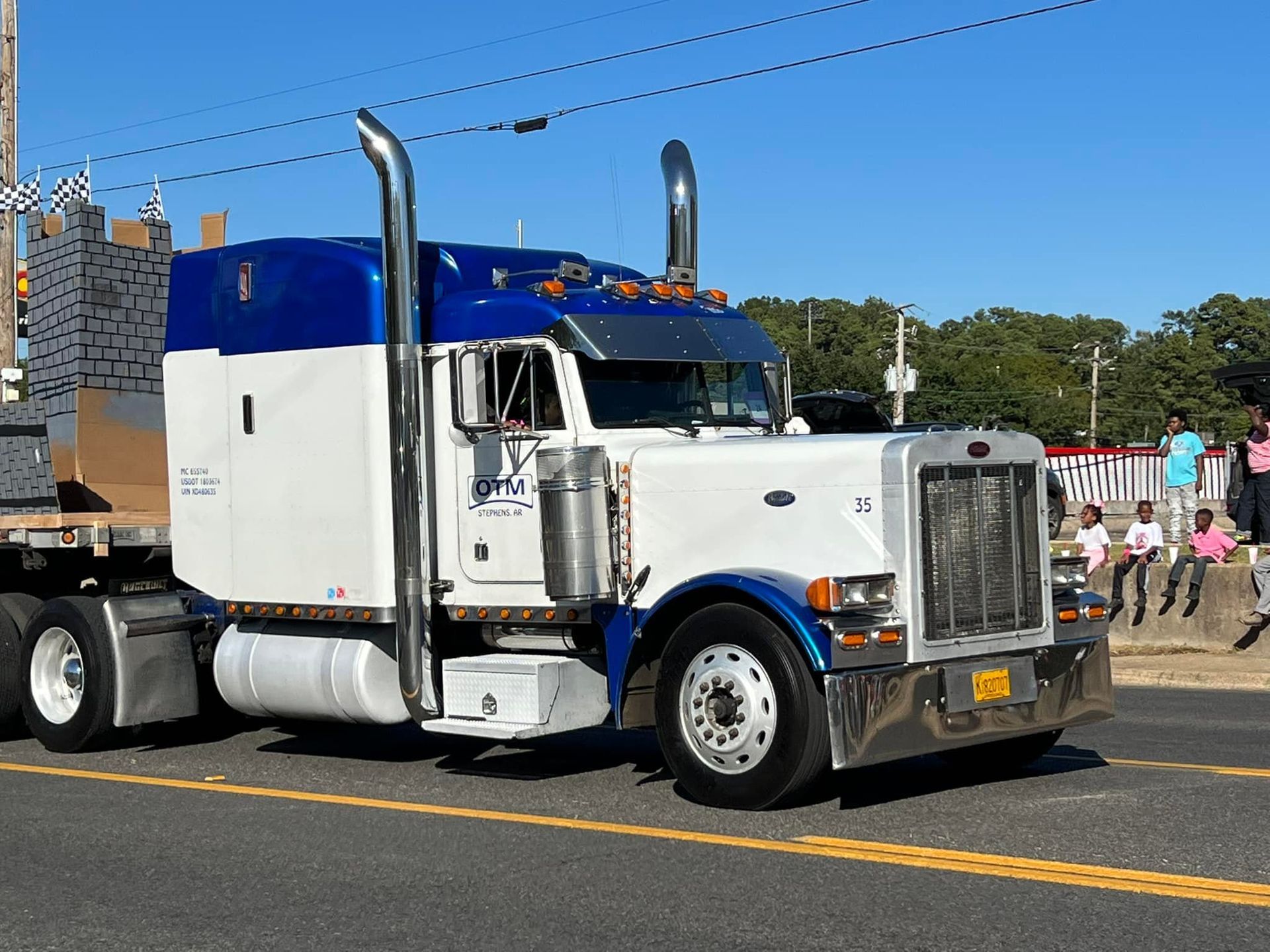 A white and blue semi truck is parked on the side of the road