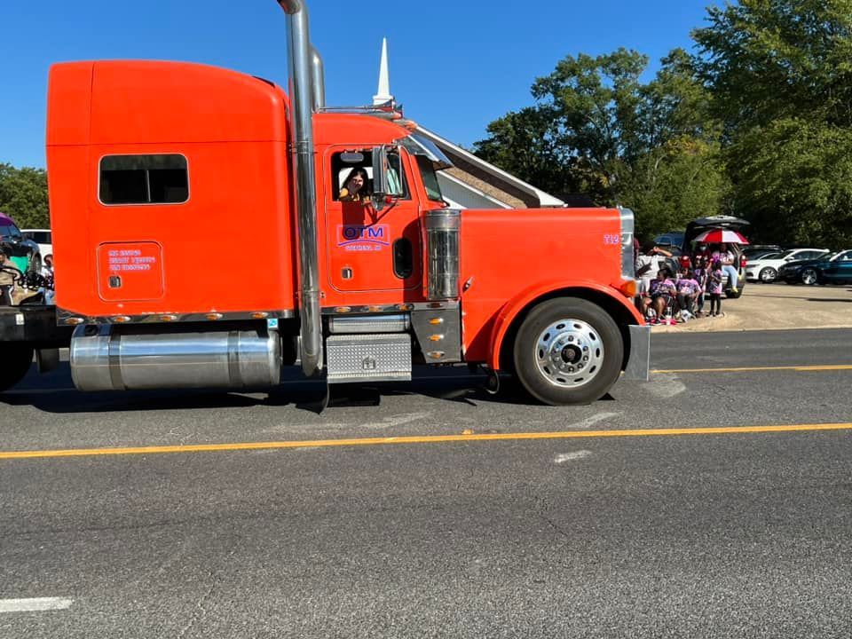 An orange semi truck is parked on the side of the road