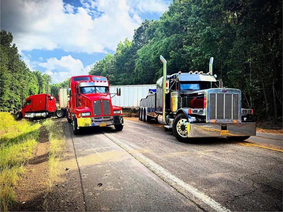 Two semi trucks are driving down a highway next to each other.