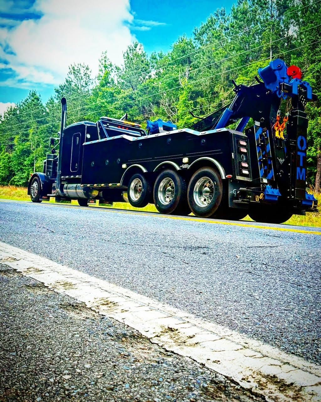 A black tow truck is parked on the side of the road