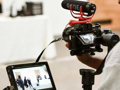 A person is holding a camera with a rode microphone attached to it.