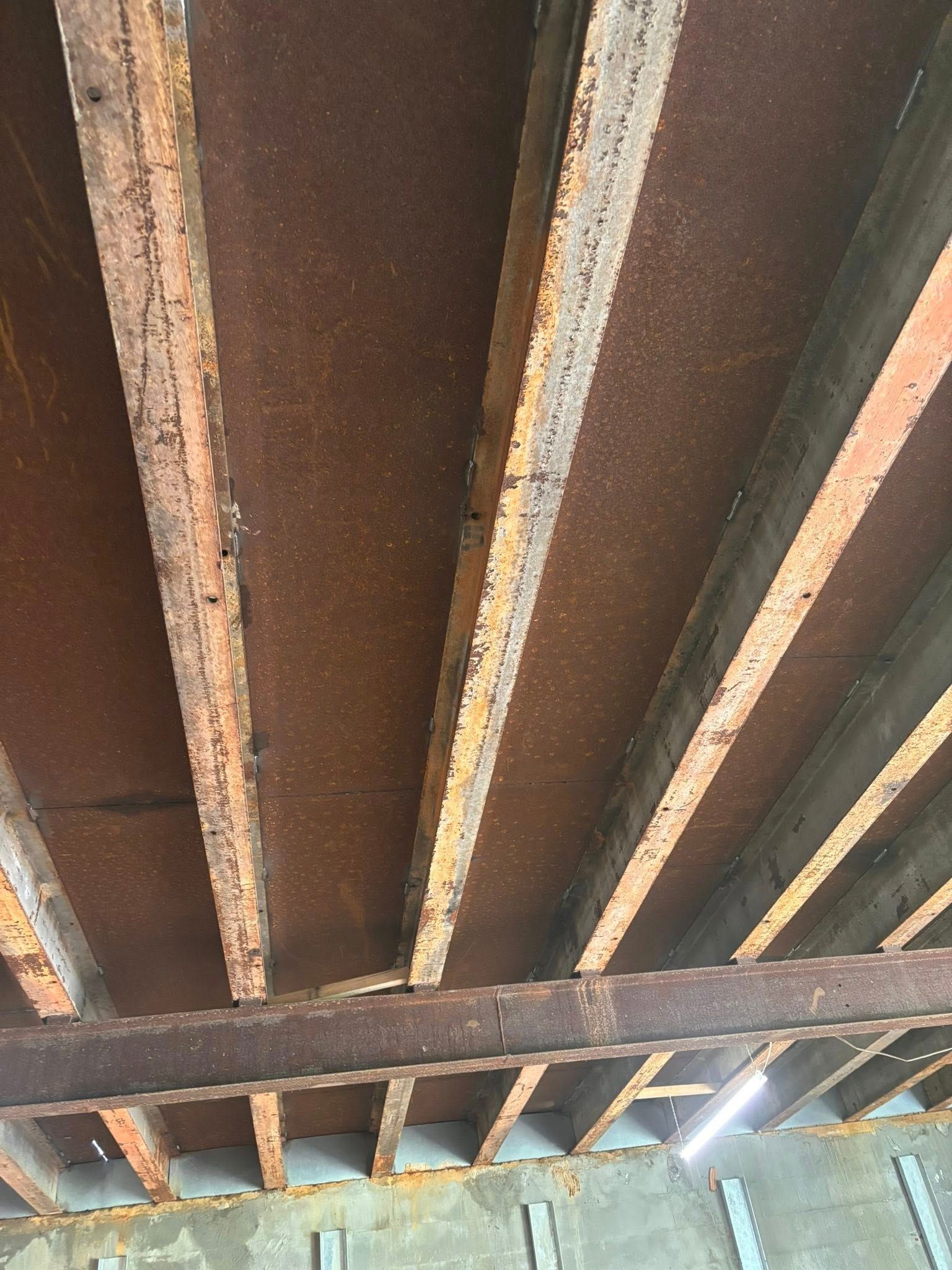 Overhead view of rusted metal beams and decking, potentially an old bridge or structure.