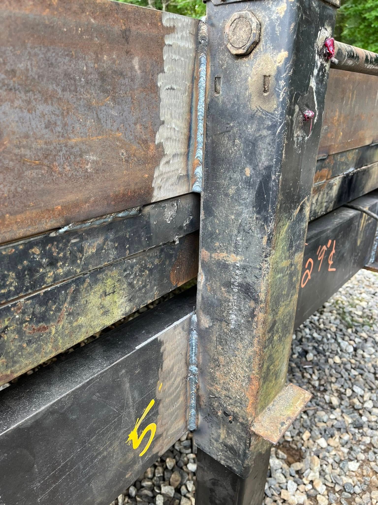 Close-up of a rusty metal truck bed and its black supporting frame with welded seams and yellow number “5”.