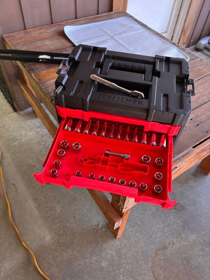 Black and red Craftsman tool chest with a drawer open, revealing a set of sockets on a wooden table.