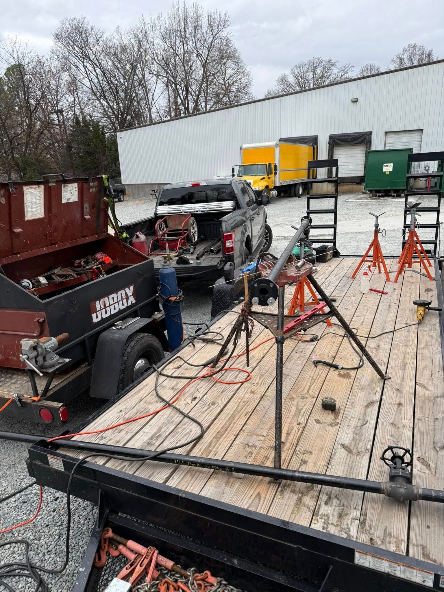 A tall white tower being worked on by a crane in an industrial setting.