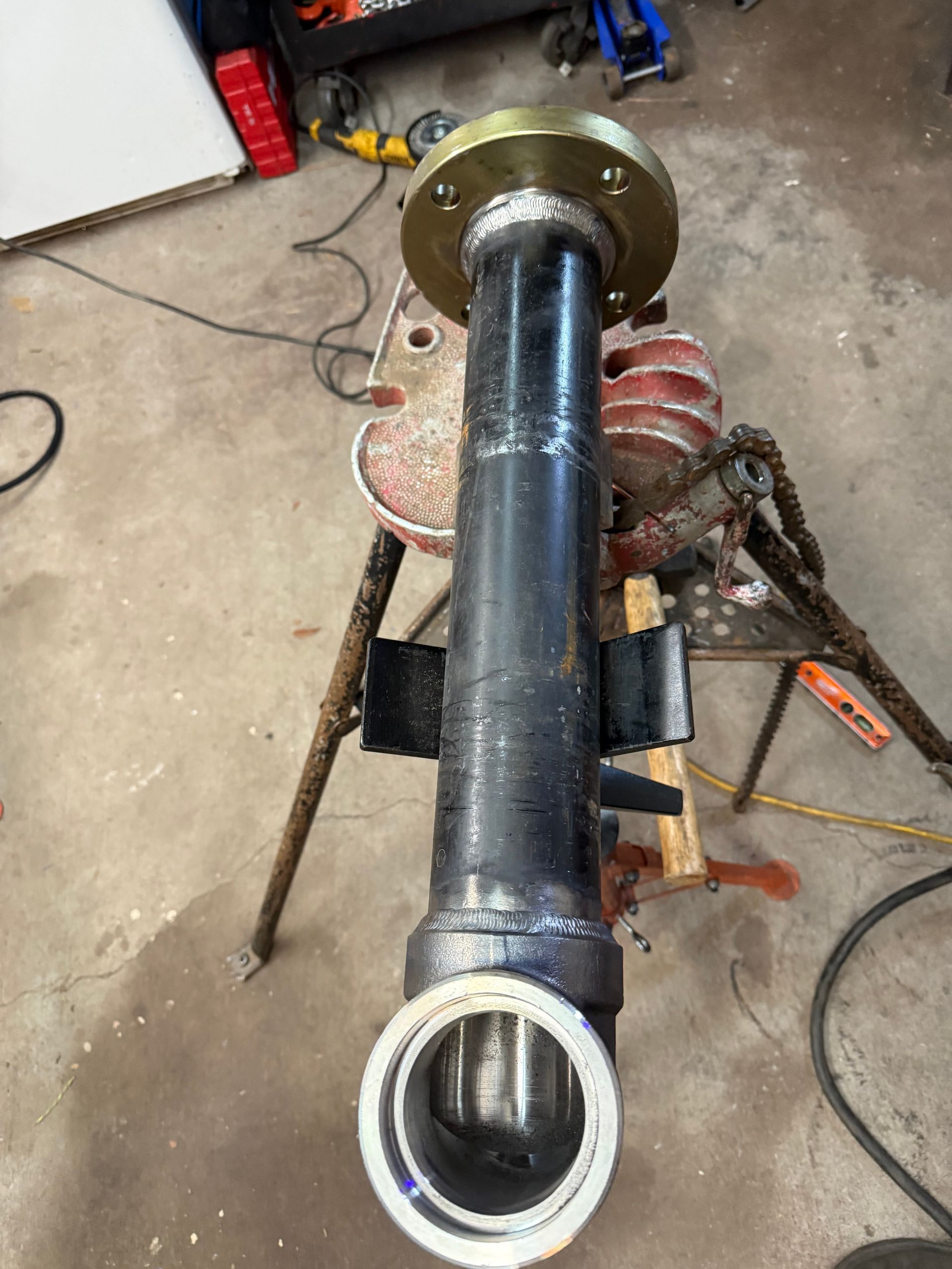 Black pipe with flange, brackets, and an opening, likely for machinery parts.