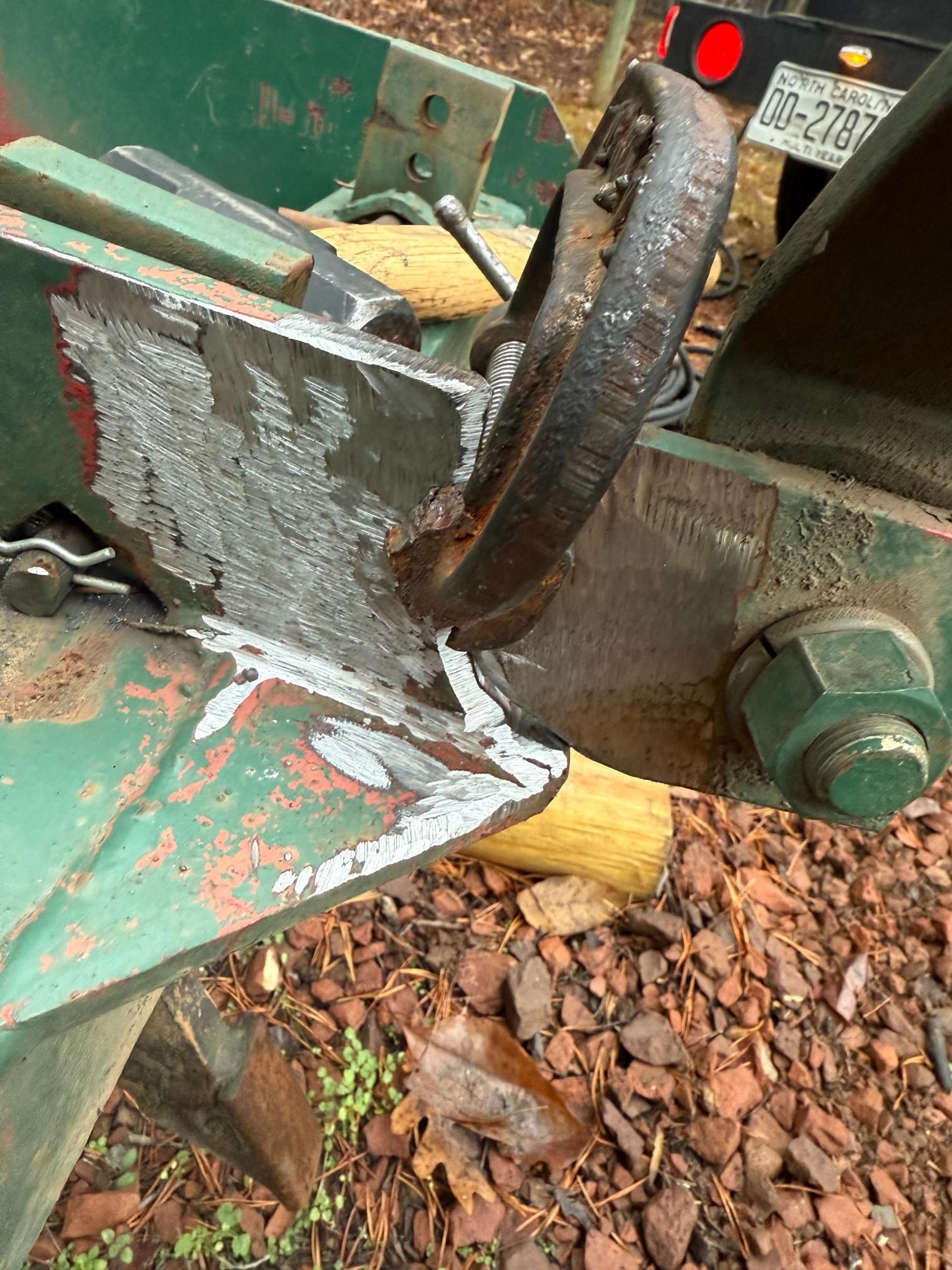 Close-up of a green farm implement with a large, rusty metal ring, showing signs of wear and repair.